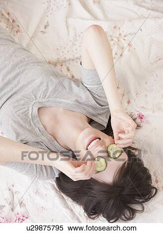 Young woman lying in bed with cucumber face mask View Large Photo Image Stock Photography - Young woman lying in bed with cucumber face mask. Fotosearch