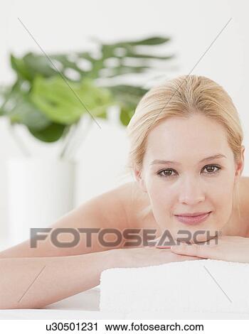 Stock Image - "Young woman lying on front and waiting for massage, portrait". Fotosearch