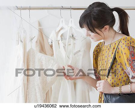 Young woman observing wedding dress in shop View Large Photo Image Stock Image - Young woman observing wedding dress in shop. Fotosearch