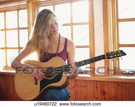 Young woman playing guitar at home View Large Photo Image Stock Image - Young woman playing guitar at home. Fotosearch