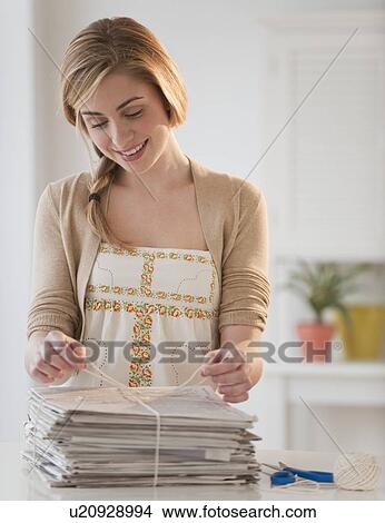 Young woman recycling newspaper in kitchen View Large Photo Image Picture - Young woman recycling newspaper in kitchen. Fotosearch