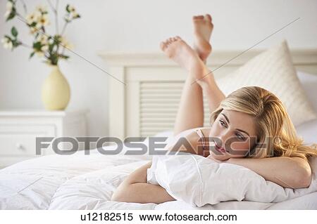 Stock Photography - Young woman relaxing on bed. Fotosearch
