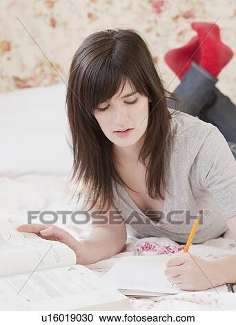 Young woman studying on bed View Large Photo Image Stock Image - Young woman studying on bed. Fotosearch