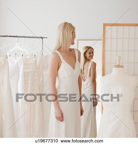 Young woman trying on wedding dress in bridal shop View Large Photo Image Stock Image - Young woman trying on wedding dress in bridal shop. Fotosearch