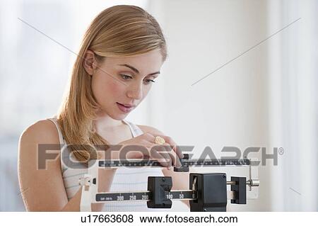Stock Photo - Young woman using measuring scales. Fotosearch