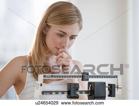 Stock Photo - Young woman using measuring scales. Fotosearch