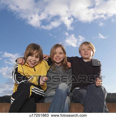 Stock Image - "3 children sitting on low wall, smiling". Fotosearch