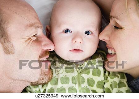 Baby laying between dad and mom View Large Photo Image Stock Photo - Baby laying between dad and mom. Fotosearch