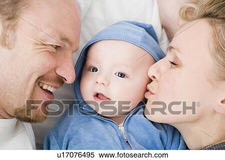 Stock Photography - Baby laying between dad and mom. Fotosearch