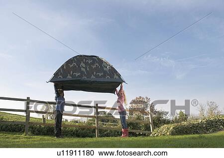 Stock Image - Boy and girl carrying tent. Fotosearch