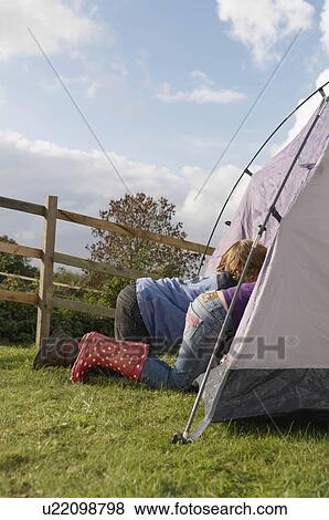 Stock Photo - Boy and girl climbing into tent. Fotosearch