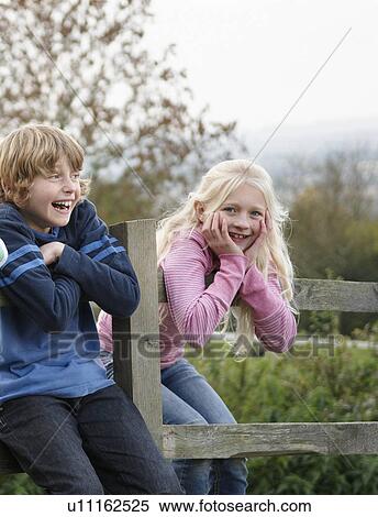 Stock Photography - Boy and girl on fence. Fotosearch