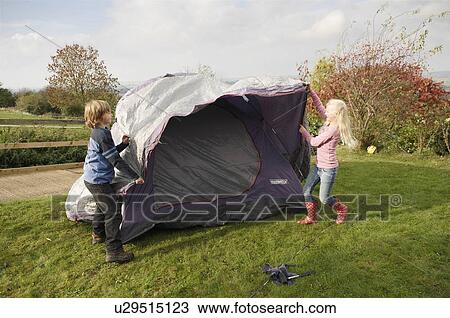 Stock Image - Boy and girl putting up tent. Fotosearch