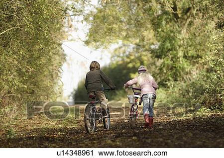 Boy and girl riding bikes in countryside View Large Photo Image Stock Image - Boy and girl riding bikes in countryside. Fotosearch