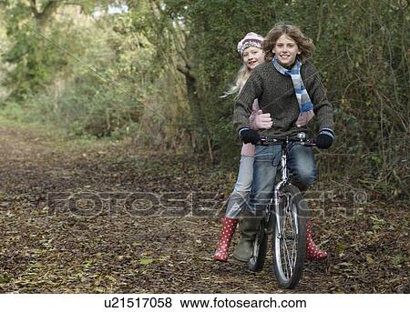Stock Photo - Boy and girl sharing bike in countryside. Fotosearch