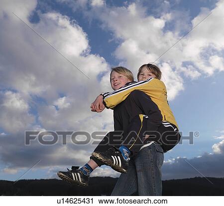 Stock Image - Boy carrying girl piggyback style. Fotosearch