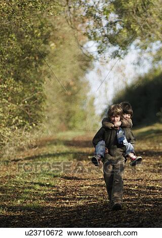 Boy carrying young child in countryside View Large Photo Image Stock Image - Boy carrying young child in countryside. Fotosearch