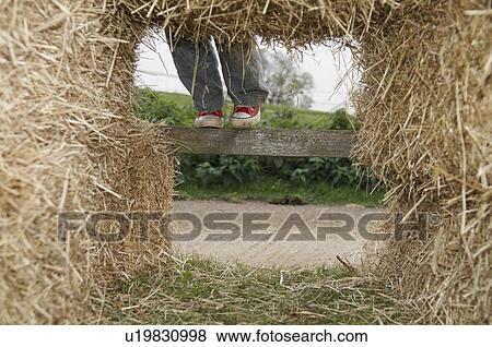 Stock Photo - Boy climbing in hay bales. Fotosearch