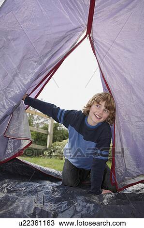 Stock Image - Boy climbing into tent. Fotosearch
