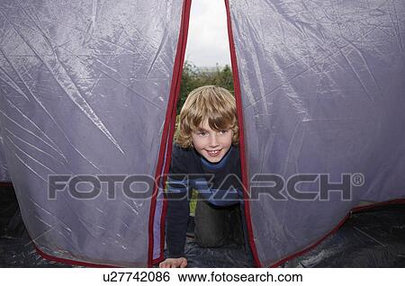Stock Photograph - Boy climbing into tent. Fotosearch