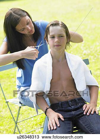 Stock Image - Boy gets his hair cut by woman. Fotosearch
