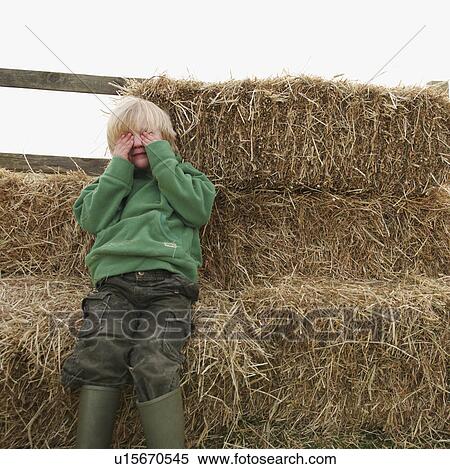 Boy hiding eyes on hay bales View Large Photo Image Stock Photography - Boy hiding eyes on hay bales. Fotosearch