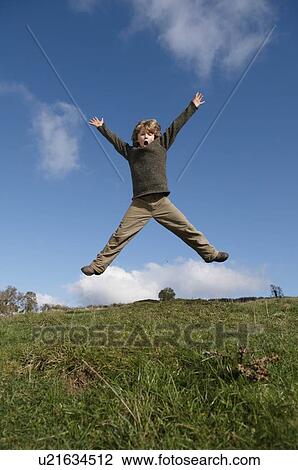 Stock Image - Boy jumping on hill. Fotosearch