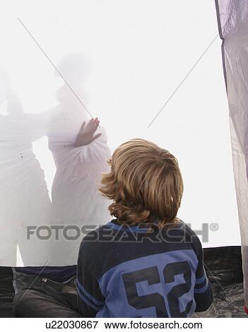 Stock Photo - Boy looking at shadows in tent. Fotosearch