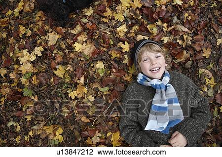 Boy lying on autumn leaves View Large Photo Image Stock Image - Boy lying on autumn leaves. Fotosearch