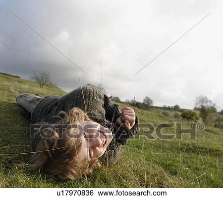 Boy lying on grass on hillside View Large Photo Image Stock Photograph - Boy lying on grass on hillside. Fotosearch