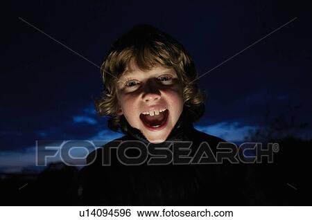 Stock Photograph - Boy making faces with flashlight. Fotosearch