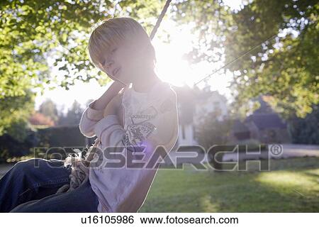 Stock Photograph - Boy on a swing. Fotosearch