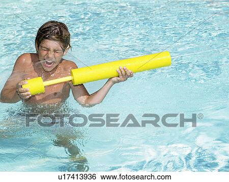 Stock Photograph - Boy playing with water gun in pool. Fotosearch
