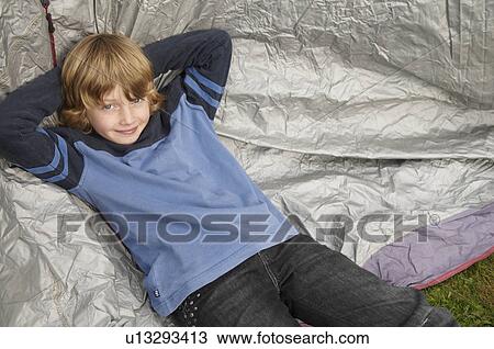 Stock Image - Boy resting on tent. Fotosearch