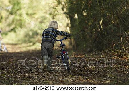 Stock Photograph - Boy walking bike in countryside. Fotosearch