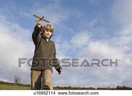 Picture - Boy with toy plane in countryside. Fotosearch