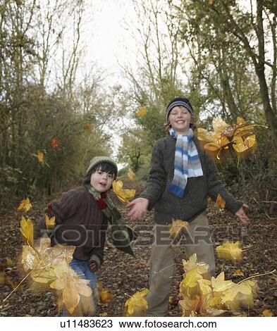 Stock Image - Boys throwing autumn leaves. Fotosearch