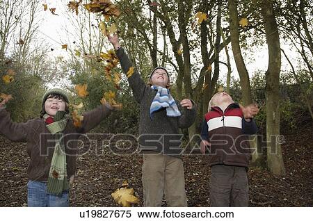 Stock Photography - Boys throwing autumn leaves. Fotosearch