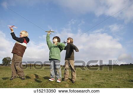 Boys throwing toy planes in field View Large Photo Image Stock Image - Boys throwing toy planes in field. Fotosearch
