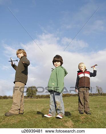 Boys throwing toy planes in field View Large Photo Image Stock Image - Boys throwing toy planes in field. Fotosearch