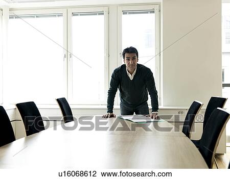 Stock Image - Business man by conference table. Fotosearch