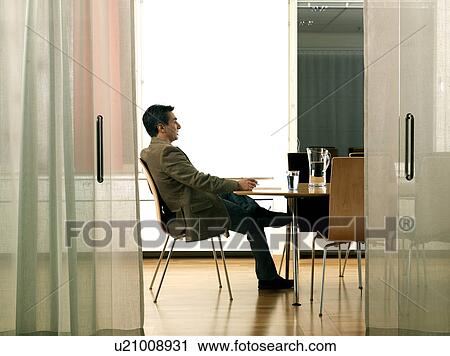 Stock Image - Business man by conference table. Fotosearch