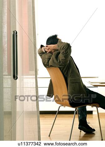 Stock Image - "Business man by desk, relaxing". Fotosearch