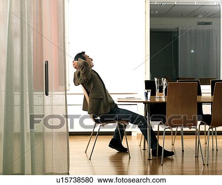 Stock Image - "Business man by desk, relaxing". Fotosearch