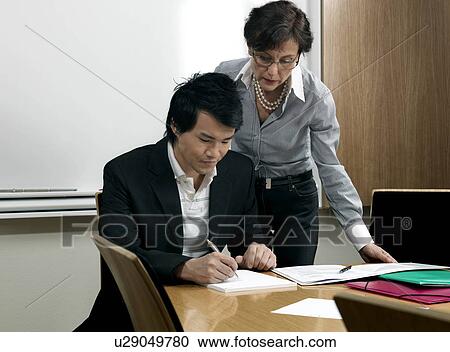 Stock Image - Business woman helping trainee. Fotosearch