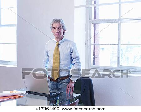 Businessman standing at table View Large Photo Image Stock Image - Businessman standing at table. Fotosearch
