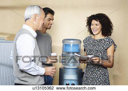 Stock Image - Casual meeting by office water cooler. Fotosearch
