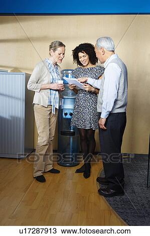 Casual meeting by office water cooler View Large Photo Image Stock Image - Casual meeting by office water cooler. Fotosearch