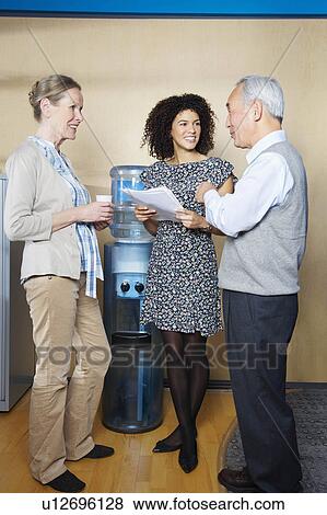 Casual meeting by office water cooler View Large Photo Image Stock Photo - Casual meeting by office water cooler. Fotosearch