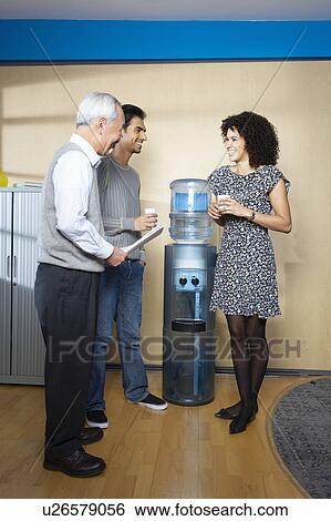 Stock Photograph - Casual meeting by office water cooler. Fotosearch